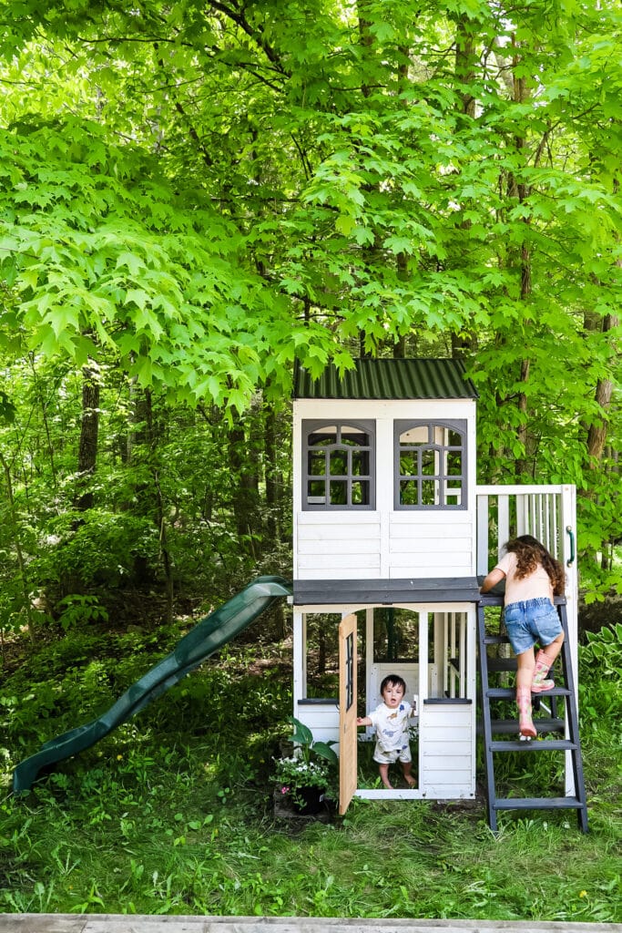 two kids playing in their woodland playhouse from Costco